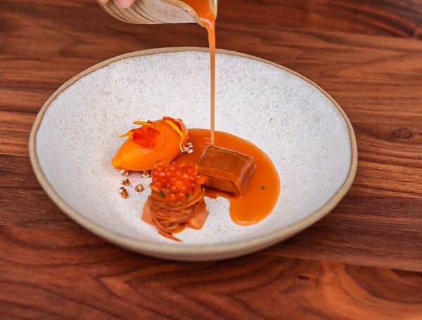 Dressage minute d'un dessert Dialogues : jus ambré versé sur sorbet abricot, caramel et œufs de truite